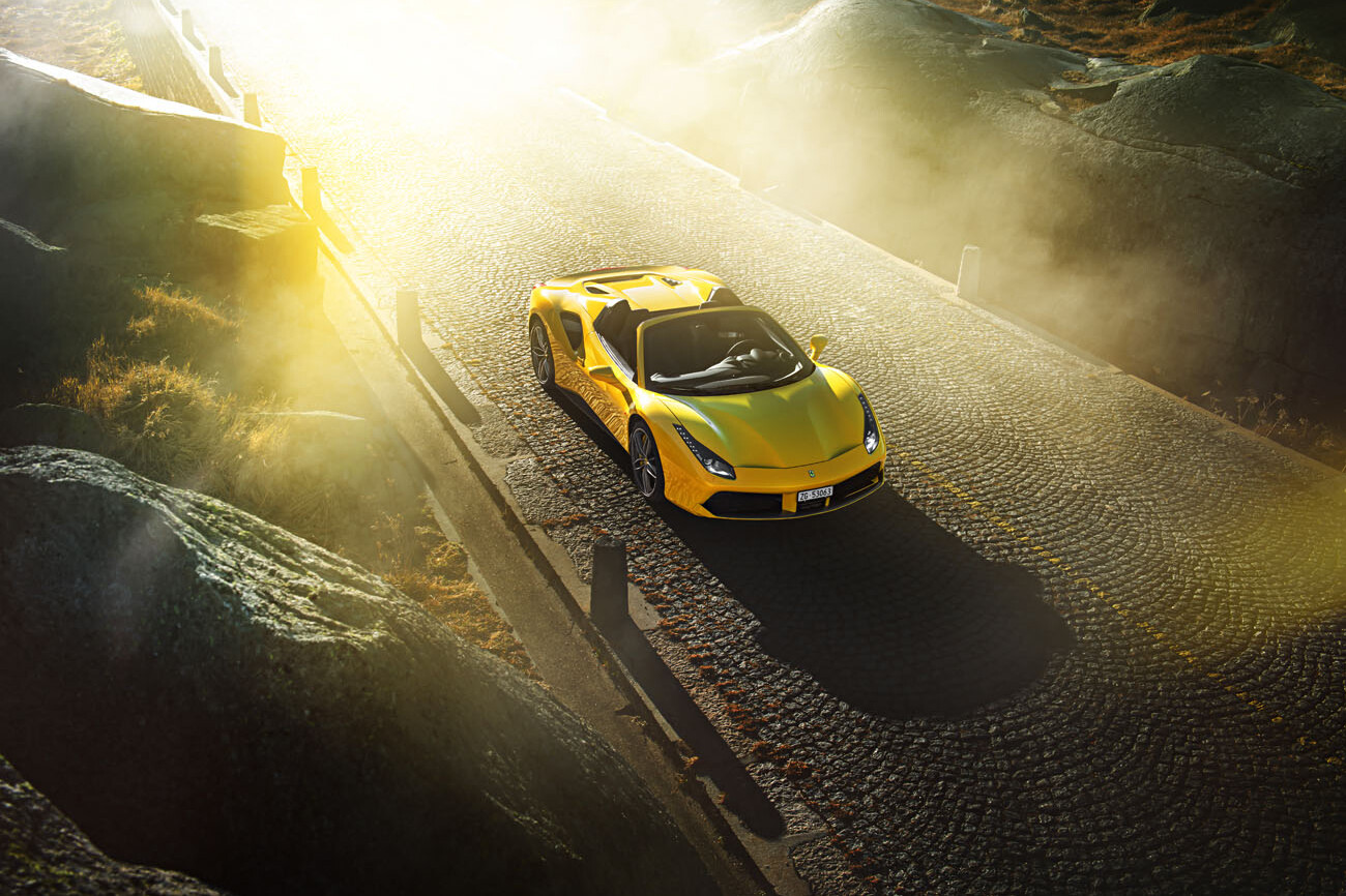 Sonnenlicht und ein gelber Ferrari 488 Spider auf der Tremola fotografiert.