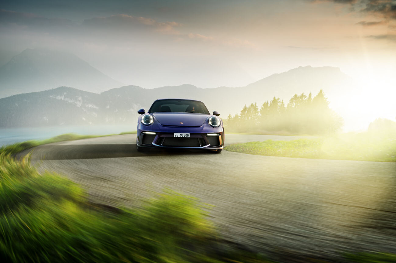 Porsche 911 GT3 Touring fährt eine Bergstrasse hoch. Im Rücken befindet sich der Vierwaldstättersee.
