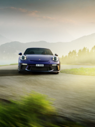 Porsche 911 GT3 Touring fährt eine Bergstrasse hoch. Im Rücken befindet sich der Vierwaldstättersee.