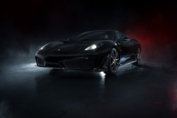 Die Front des schwarzen Ferrari 430 Scuderia mit brennenden Scheinwerfern.